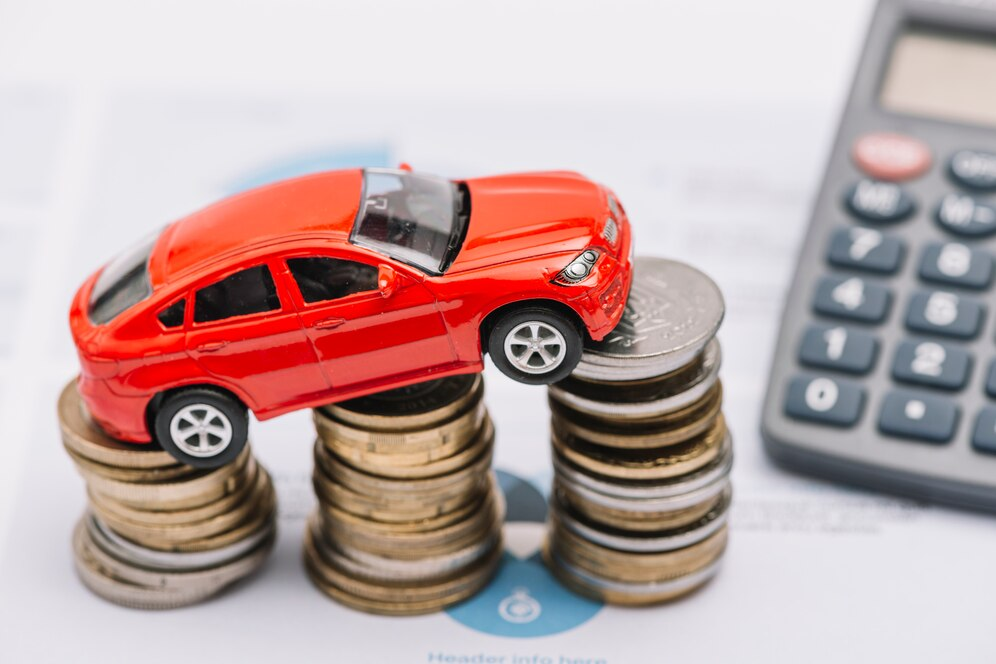 Toy car atop a stack of accelerating coins with a calculator on the side.