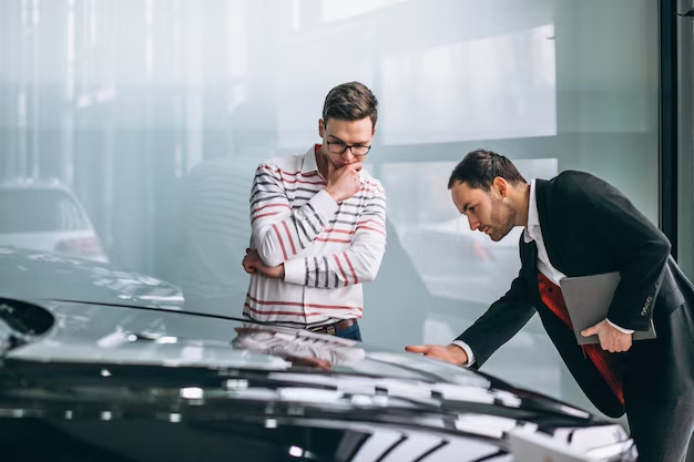 Two individuals examining a car